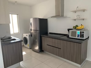 Enjoy cooking in this well-equipped kitchen with a refrigerator, washing machine, and microwave.
