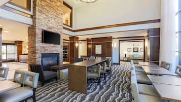 A hotel lobby with a fireplace, seating area, and a conference table.