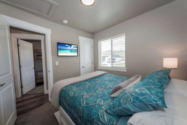 Une chambre à coucher comprenant un lit, une télévision, une fenêtre et une porte donnant sur un couloir.