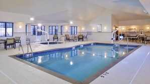 An indoor swimming pool with lounge chairs, a lifeguard stand, and a sign indicating a 5'0 height limit.