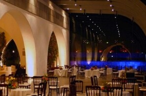 A dining area with tables and chairs, a stage with blue lighting, and a large arched structure. - Gallaecia Hotel Boutique (Santa Catarina)