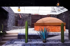 A courtyard with a stone wall, a brick structure, and cacti. - Gallaecia Hotel Boutique (Santa Catarina)