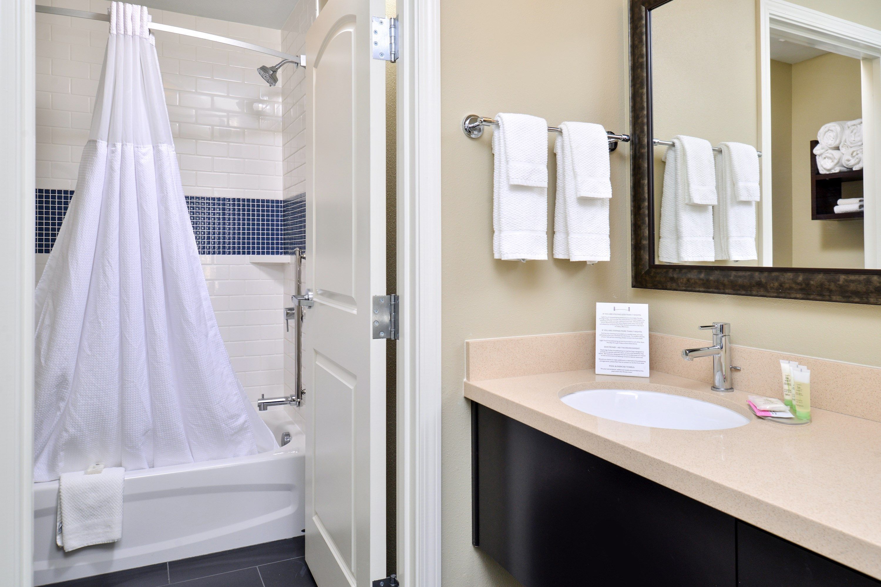 A bathroom with a bathtub, a sink, a mirror, and a towel rack with multiple towels.