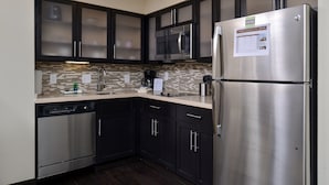 A modern kitchen with dark cabinets, stainless steel appliances, a microwave, and a refrigerator. - Cozy Suite in Rochester | Free Breakfast + Shared Pool & Hot Tub. Near Mayo Clinic! (Rochester)