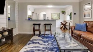 A modern living room with a glass coffee table, a brown leather sofa, and a blue and white patterned rug. - Walk to Falls / Close to Everything / Fenced Backyard (Minneapolis)