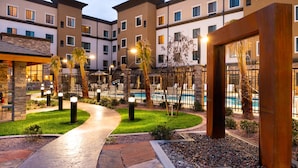 A hotel courtyard with a swimming pool, stone pathway, and palm trees. - Relaxing Retreat! Shared Pool & Hot Tub + Free Breakfast (St George)