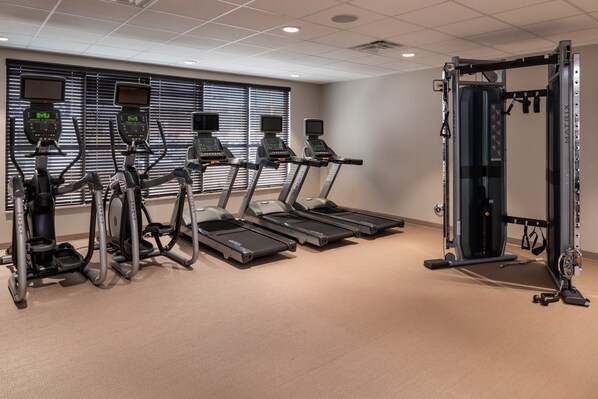A gym with treadmills, elliptical machines, and a weightlifting station.