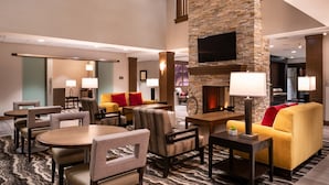 A spacious lobby with a stone fireplace, comfortable seating, and a modern design. - King Suite | Access to Free Breakfast + Shared Pool & Hot Tub. Your Next Vacation! (St George)