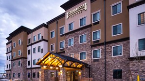 Un hotel Staybridge Suites con fachada de piedra, múltiples ventanas y un área de acceso cubierta.