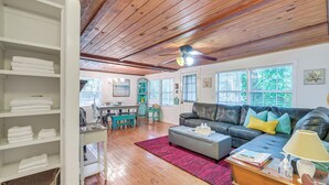 A spacious living room with a wooden ceiling, a black leather sofa, a grey ottoman, and a red rug. - 2 Mi to Marina: Inglis Retreat w/ Boat Parking (Inglis)