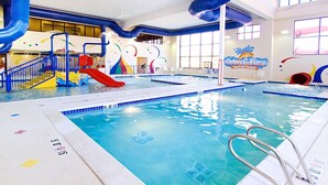Una piscina interior con tobogán, zona de juegos acuáticos y un cartel para el parque acuático Grin & Fins.