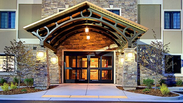Fachada de edificio de piedra, arco de madera y puerta de cristal.