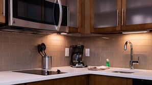 A modern kitchen with stainless steel appliances, wooden cabinets, and a white countertop.