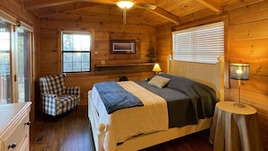 Une chambre confortable dans un chalet en rondins, avec un lit, une chaise, une commode et un ventilateur de plafond.