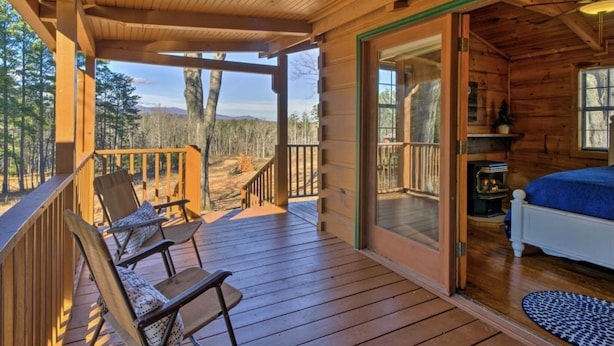 Une cabane en bois avec une véranda, un lit et une cheminée.