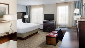 Une chambre d’hôtel comprenant un lit, un bureau, une télévision, une commode et une lampe.