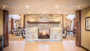 A spacious lobby with a stone fireplace, wooden flooring, and a dining area with chairs and tables. - Accessible 1-Bedroom Suite in Folsom, CA (Folsom)