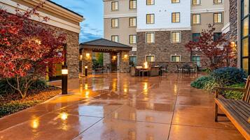 Evening courtyard with a fire pit, outdoor seating, and potted plants.