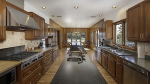 A modern kitchen with wooden cabinets, a central island, and a view to the outdoors.