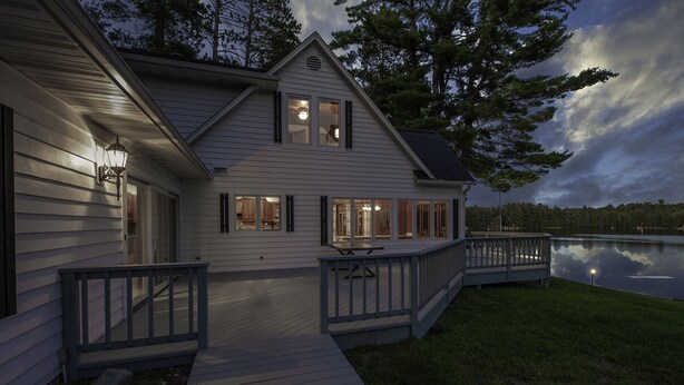 A two-story house with a deck and a lake view.