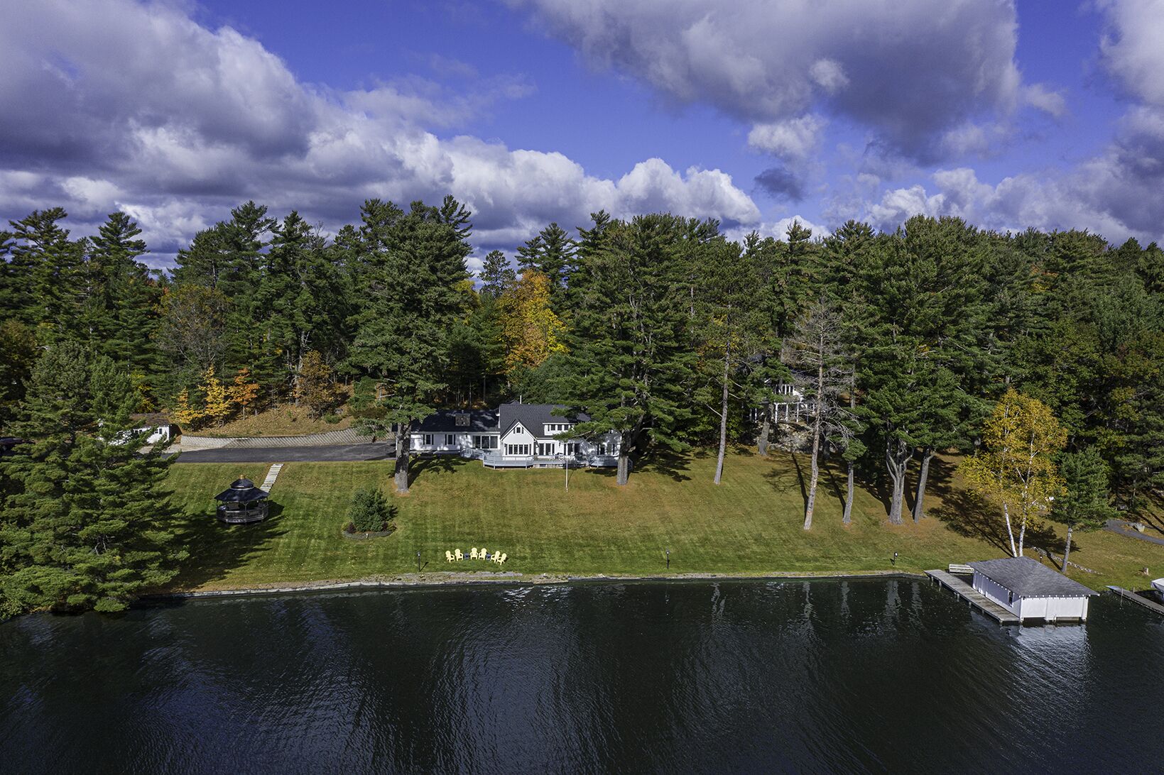 Una casa grande rodeada de árboles frondosos y un lago.