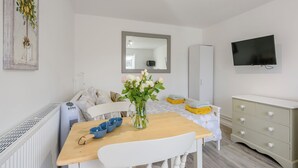 Habitació moderna i ben il·luminada amb una taula de dinar, cadires, un televisor i un armari.