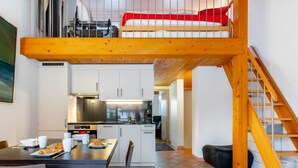 Ein stilvolles Loft mit einer Holztreppe, einer Küchenzeile und einem Essbereich.