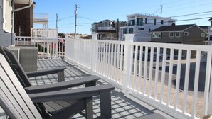 Un balcón con dos sillas y una mesita, con vistas a una zona residencial con casas y líneas eléctricas.