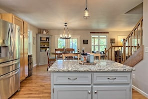 Enjoy cooking in this well-appointed kitchen with a granite countertop island, stainless steel appliances, and a dining area with a wooden table and chairs.