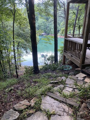 Overlooking a serene lake, this deck offers a peaceful retreat surrounded by lush greenery and tall trees.