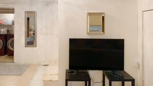 A living room with a flat-screen TV, a small table, and a mirror on the wall. - GREAT HOME! GREAT LOCATION! PET FRIENDLY  (Kissimmee)