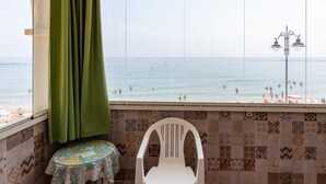Una habitación con vista a la playa, una silla, una mesita y baldosas con diseño.