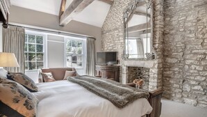 Een slaapkamer met een stenen muur, een groot bed, een televisie en een open haard.