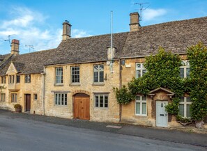 A traditional stone building with a wooden door, multiple windows, and a chimney.