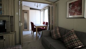 Ein gemütlicher Wohnbereich mit einer Couch, einem Esstisch mit Stühlen und einem Fernseher auf einem Schrank.