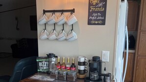 Een keukentafel met een koffieapparaat, potten met koffiebonen en een bordje met de tekst 'Coffee and Tea Makes the Perfect Blend'.