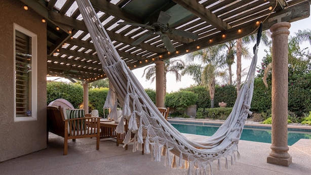 A hammock under a pergola with string lights, a pool, and outdoor furniture. - Sunset Disco: Large Pool/Spa @ Lush Family Retreat (La Quinta)