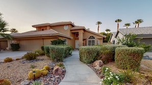 A residential house with a paved driveway, surrounded by well-maintained hedges and cacti. - Sunset Disco: Large Pool/Spa @ Lush Family Retreat (La Quinta)