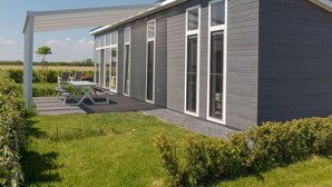 Una casa moderna con un porche cubierto, ventanas amplias y un césped bien cuidado.