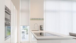 Una cocina moderna con una isla central, horno empotrado y ventana con vistas a un balcón.