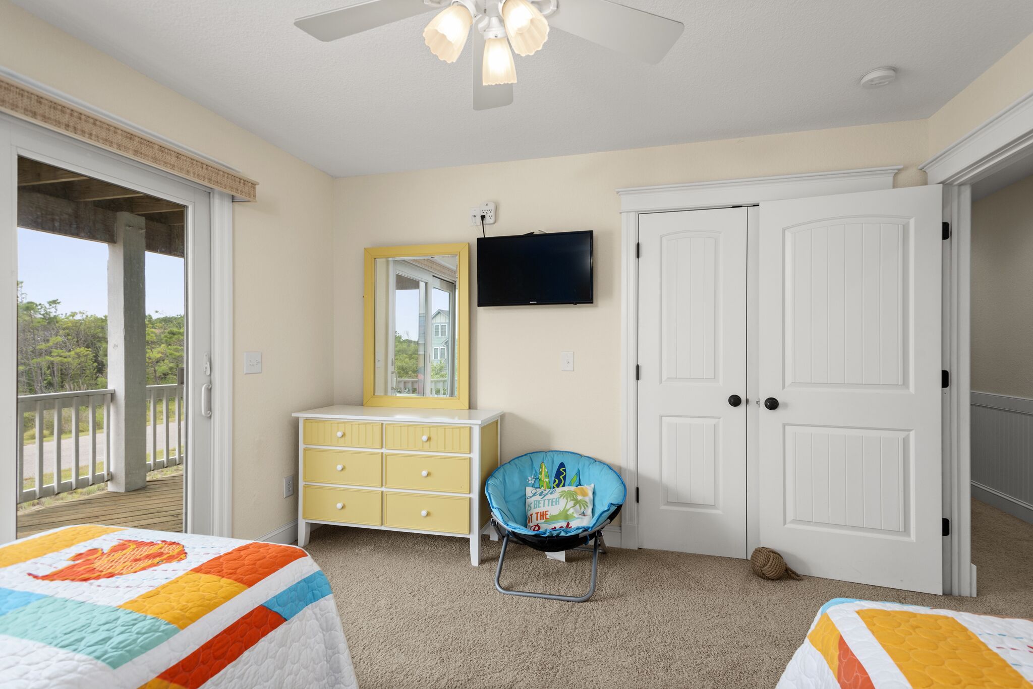 Un dormitorio con cama, cómoda, silla, televisor y puerta.