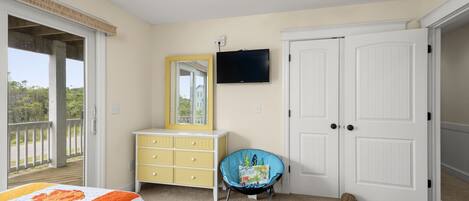 Un dormitorio con cama, cómoda, silla, televisor y puerta.