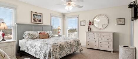 A bedroom with a bed, dresser, and ceiling fan.
