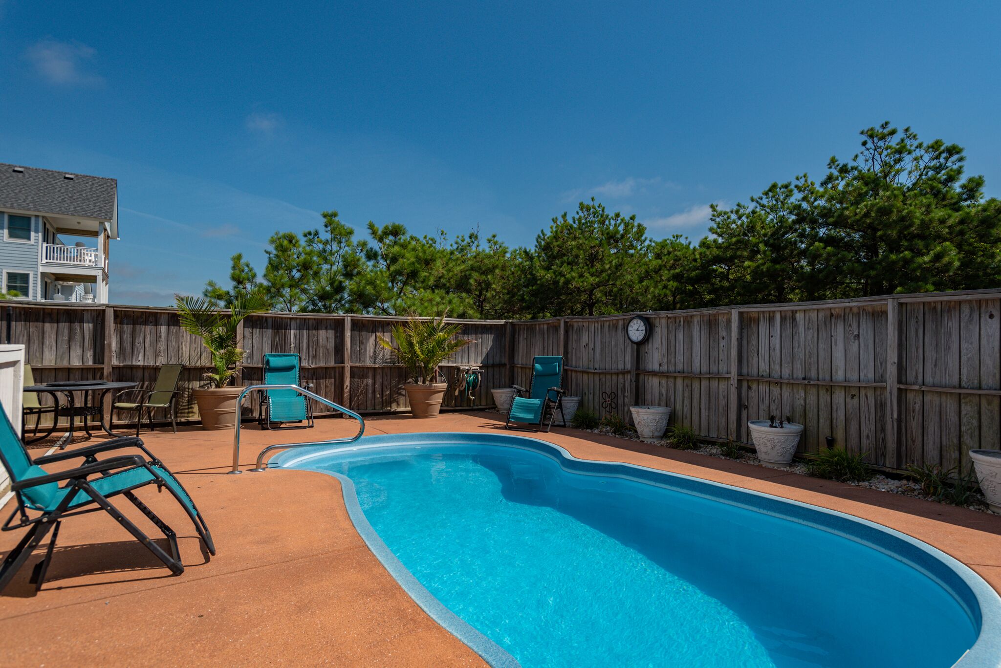 A backyard with a swimming pool, wooden fence, and outdoor furniture.