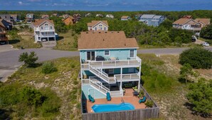 A two-story house with a pool, surrounded by a wooden fence, and located in a residential area with other houses. - Haven Of Rest: Private Saltwater Pool, Hot Tub, Game Room (Nags Head)