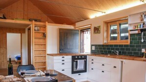 A compact kitchen with white cabinets, a built-in oven, and a window above the sink. - Rustico Rudico by Interhome (Semione)