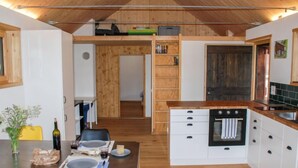 A compact kitchen with white cabinets, a black oven, and a wooden countertop. - Rustico Rudico by Interhome (Semione)