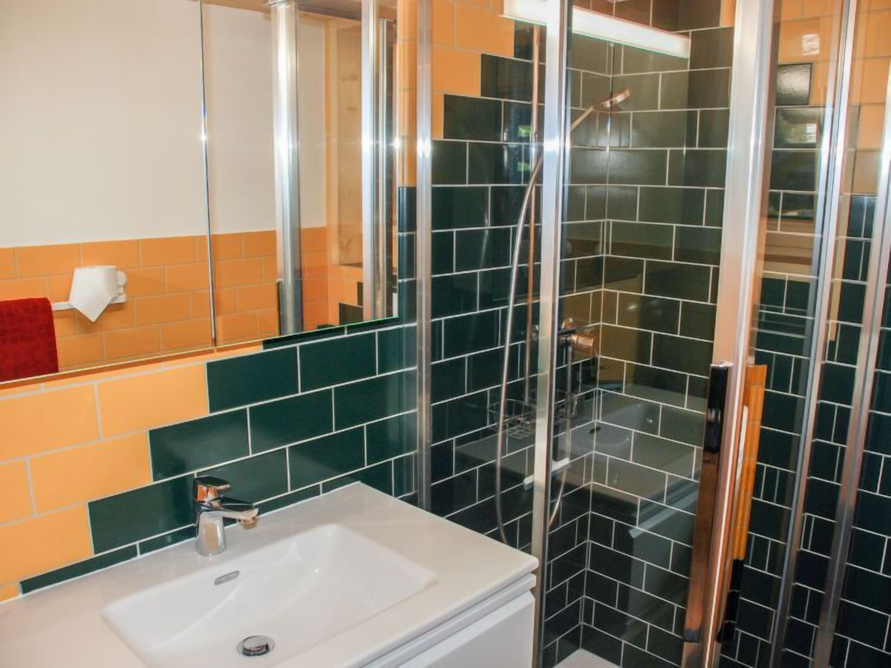 Un bagno con lavandino bianco, cabina doccia in vetro e specchio.