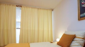 Een hotelkamer met een bed, nachtkastje, lamp en een schilderij aan de muur.
