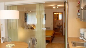 Een hotelkamer met een bed, een eettafel met stoelen, een keukenhoek met een spoelbak en een spiegel.